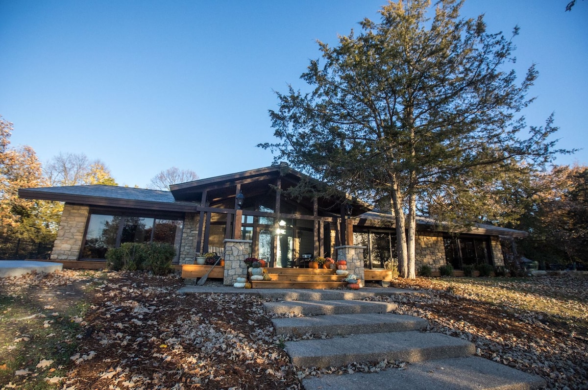 Stone riverfront house surrounded by autumn leaves and pumpkins