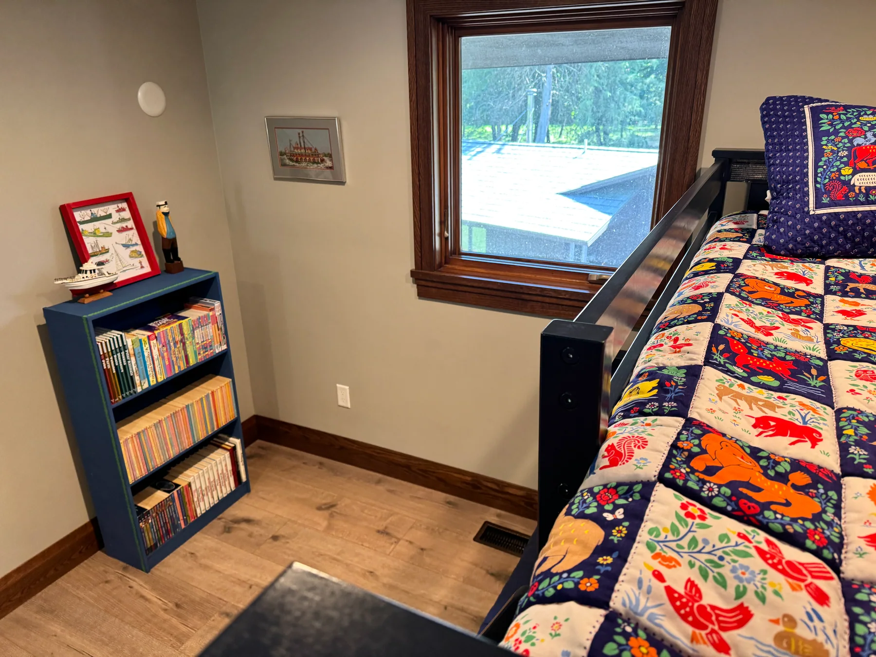 A colorful top bunk beside a blue bookcase filled with children’s books at Grey Cloud Island